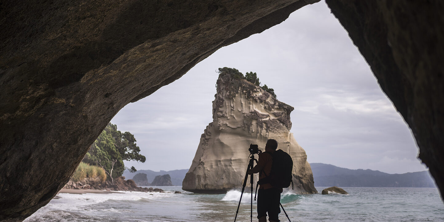 Photographer taking a photo at Cathedral Cove, Coromandel Peninsula, New Zealand North Island Photographer taking a photo at Cathedral Cove, Coromandel Peninsula, New Zealand North Island